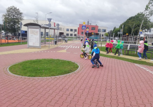 chłopiec z dziewczynką jadą na rowerkach przez rondo